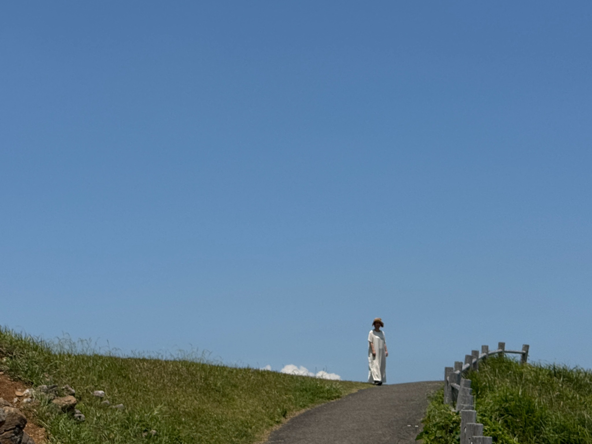 大きな青空の下を歩く白い服の人物